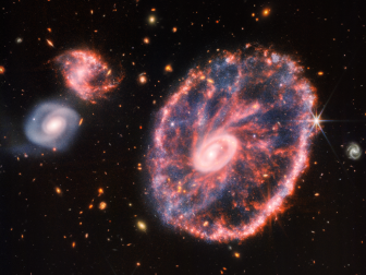 This image from Webb’s Mid-Infrared Instrument (MIRI) shows a group of galaxies, including a large distorted ring-shaped galaxy known as the Cartwheel. The Cartwheel Galaxy, located 500 million light-years away in the Sculptor constellation, is composed of a bright inner ring and an active outer ring. While this outer ring has a lot of star formation, the dusty area in between reveals many stars and star clusters.